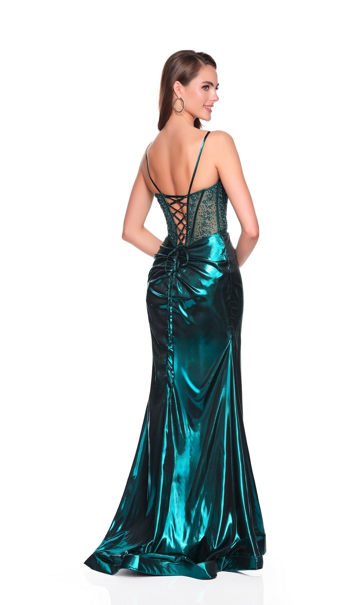 A woman models the Dave and Johnny 12886 long prom dress in metallic emerald green, featuring a corset bodice, lace-up back, ruched skirt, and thigh-high slit against a white background.